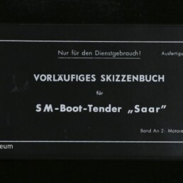 Schwarzer Einband eines Hefts mit weißem Rahmen und weißer Aufschrift „VORLÄUFIGES SKIZZENBUCH für SM-Boot-Tender ‚Saar‘“, oben der Hinweis „Nur für den Dienstgebrauch!“, links unten Logo und Schriftzug des Internationalen Maritimen Museums Hamburg; Rücken mit Klebestreifen sichtbar.