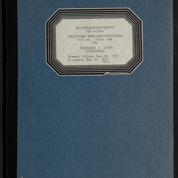 Blauer Buch‑/Ordnerumschlag mit schwarzem Rücken, oben mittig ein weißes, schwarz gerahmtes achteckiges Etikett mit gedrucktem deutschen Text zu einer Schiffbauvorschrift für einen deutschen Mehrzweckfrachter und unten links das Logo des Internationalen Maritimen Museums Hamburg