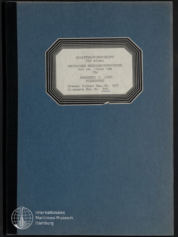 Blauer Buch‑/Ordnerumschlag mit schwarzem Rücken, oben mittig ein weißes, schwarz gerahmtes achteckiges Etikett mit gedrucktem deutschen Text zu einer Schiffbauvorschrift für einen deutschen Mehrzweckfrachter und unten links das Logo des Internationalen Maritimen Museums Hamburg
