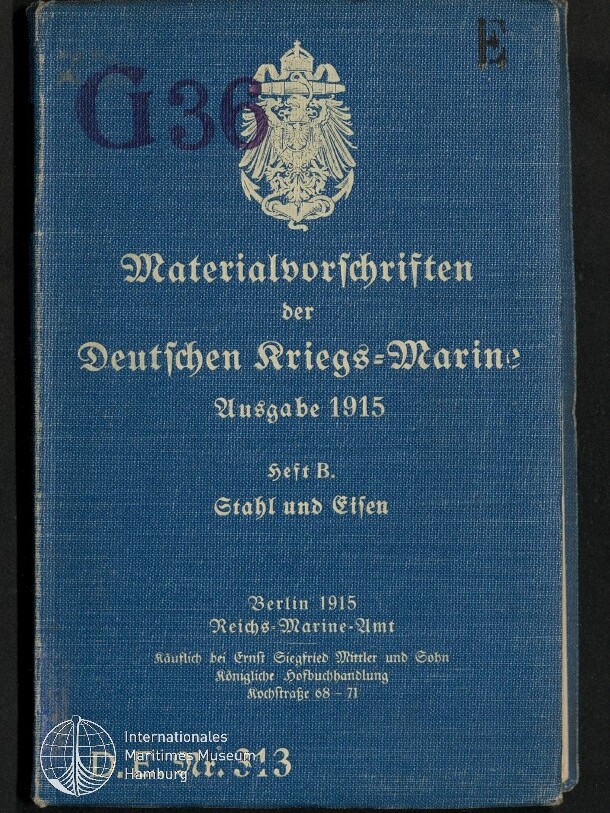Buchdeckel eines blau bezogenen Hefts mit weißer Prägung: preußischer Reichsadler oben und der Titel Materialvorschriften der Deutschen Kriegs‑Marine Ausgabe 1915, Heft B: Stahl und Eisen; Stempel G39 oben links und Museumssignet unten links.