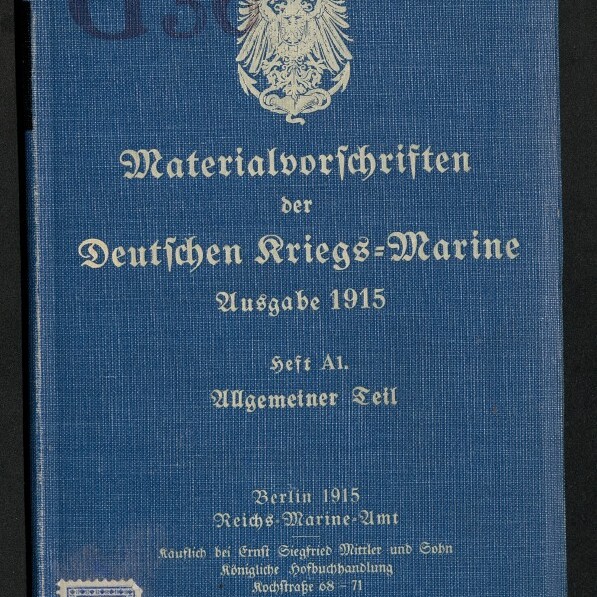 Blaues Buchcover mit weißem Reichsadler oben und in Frakturschrift der Titel ‚Materialvorschriften der Deutschen Kriegs‑Marine, Ausgabe 1915, Heft A1 Allgemeiner Teil‘ sowie Verlagsangaben und Museumsstempel unten links.