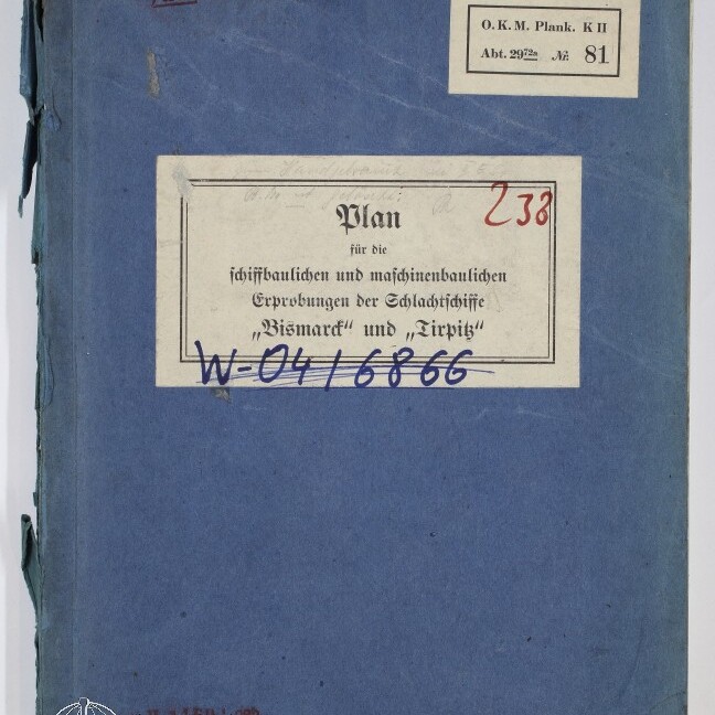 Blaues, leicht abgenutztes Heft mit mehreren Papieretiketten: zentrales weißes Etikett mit dem gedruckten Titel Plan für die schiffbaulichen und maschinenbaulichen Erprobungen der Schlachtschiffe Bismarck und Tirpitz, handschriftlichen roten und blauen Vermerken sowie kleinem Etikett oben rechts und Museumslogo unten links.