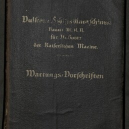 Schwarzer, leicht abgenutzter Lederumschlag mit goldgeprägter Frakturschrift; unten steht deutlich „Wartungs-Vorschriften“, darüber Hinweise zur Bauart für U-Boote der Kaiserlichen Marine, unten links das Logo des Internationalen Maritimen Museums Hamburg.