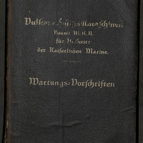 Schwarzer, leicht abgenutzter Lederumschlag mit goldgeprägter Frakturschrift; unten steht deutlich „Wartungs-Vorschriften“, darüber Hinweise zur Bauart für U-Boote der Kaiserlichen Marine, unten links das Logo des Internationalen Maritimen Museums Hamburg.