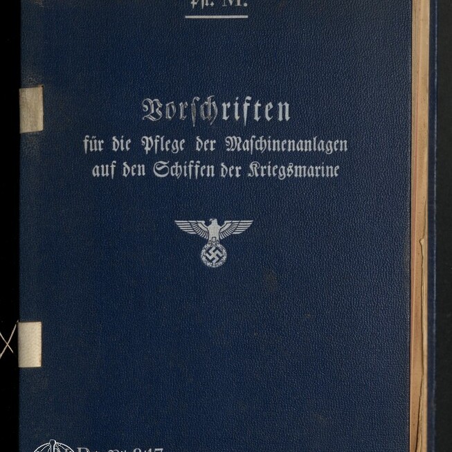 Dunkelblauer Hardcover-Einband mit weißer Frakturschrift 'Vorschriften für die Pflege der Maschinenanlagen auf den Schiffen der Kriegsmarine' und einem Hoheitsadler mit Hakenkreuz, oben links ein Etikett und unten links das Logo des Internationalen Maritimen Museums Hamburg.