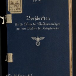 Dunkelblaues Einbandbuch mit silberner Frakturschrift 'Vorschriften für die Pflege der Maschinenanlagen auf den Schiffen der Kriegsmarine', oben die Abkürzung 'Pfl. M.', in der Mitte ein Reichsadler mit Hakenkreuz sowie links oben kleine Etiketten und unten links das Signet des Internationalen Maritimen Museums Hamburg.