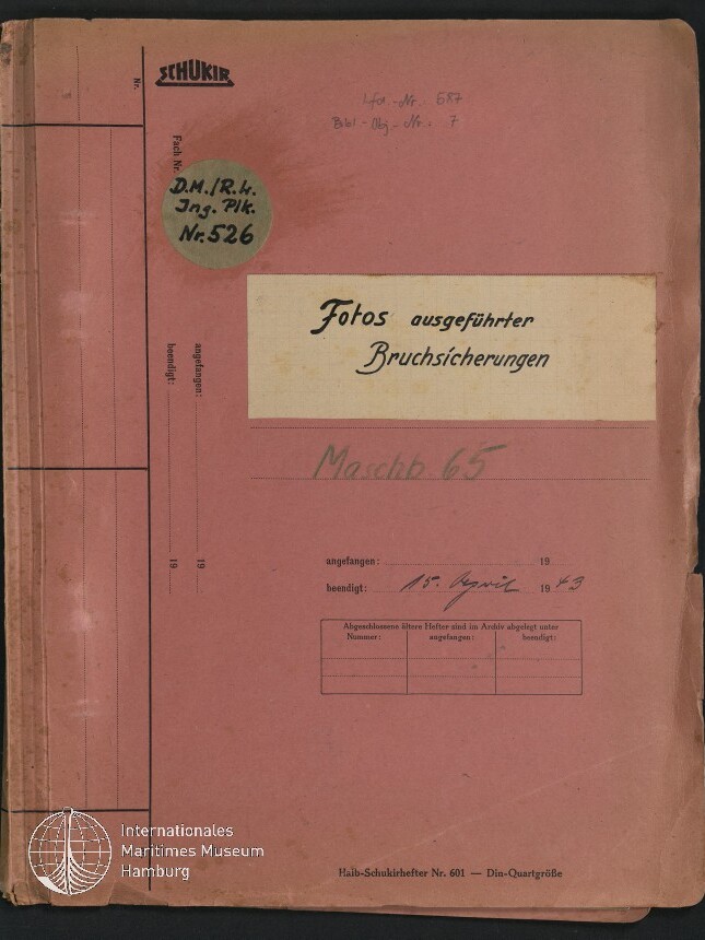 Abgenutztes rosa Aktenheft mit dem Titel 'Fotos ausgeführter Bruchsicherungen' in schwarzer Schrift, einem runden Etikett 'D.M.R.H. Ing. Plk. Nr.526', handschriftlichen Notizen (u. a. 'Maschb.65' und Datum 15. April 1943) sowie dem Logo des Internationalen Maritimen Museums Hamburg in der unteren linken Ecke.