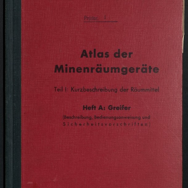Rotes Leinenbuch mit schwarzem Rücken und schwarzer Aufschrift ‚Atlas der Minenräumgeräte – Teil I: Kurzbeschreibung der Räummittel, Heft A: Greifer‘; oben steht ‚Deutsche Minenräumdienstvorschrift Nr. 11‘ und unten ist das weiße Signet des Internationalen Maritimen Museums Hamburg zu sehen.