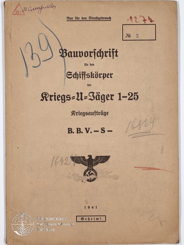 Titelblatt einer beigefarbenen Dienstvorschrift von 1941 mit der Überschrift 'Bauvorschrift für den Schiffskörper der Kriegs-U-Jäger 1–25', NS-Reichsadler über Hakenkreuz, zahlreichen handschriftlichen Notizen und Stempeln (u. a. 'Geheim!') sowie Wasserzeichen des Internationalen Maritimen Museums Hamburg.
