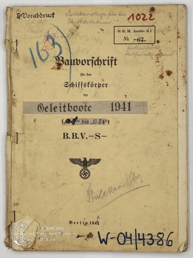 Vergilbtes, fleckiges Deckblatt eines gebundenen technischen Hefts von 1941 mit dem Titel „Bauvorschrift für den Schiffskörper der Geleitboote“, handschriftlichen Anmerkungen, Nummernstempeln und dem Reichsadler mit Hakenkreuz, sichtbaren Knicken und abgesplittertem Buchrücken.