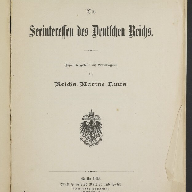 Titelblatt einer Publikation mit dem Schriftzug „Die Seeinteressen des Deutschen Reichs“ in Frakturschrift, zentriertem Reichsadler-Emblem, Verlagsangabe „Berlin 1898“ unten, Museumsstempel links unten und leicht beschädigtem, eingeknicktem rechten Seitenrand.