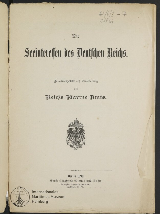 Titelblatt einer Publikation mit dem Schriftzug „Die Seeinteressen des Deutschen Reichs“ in Frakturschrift, zentriertem Reichsadler-Emblem, Verlagsangabe „Berlin 1898“ unten, Museumsstempel links unten und leicht beschädigtem, eingeknicktem rechten Seitenrand.