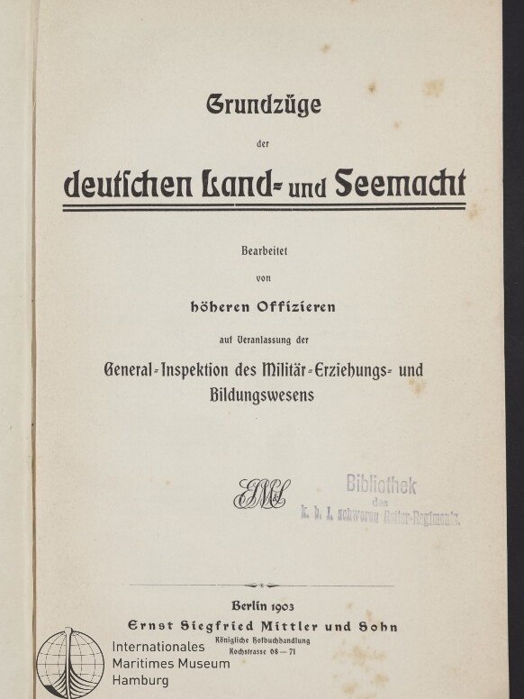 Titelblatt eines Buches mit der Überschrift „Grundzüge der deutschen Land- und Seemacht“, darunter Herausgeber- und Inspektionsangaben, ein Bibliotheksstempel, Verlagsangabe Berlin 1903 (Ernst Siegfried Mittler und Sohn) und ein Museumssignet unten links auf leicht fleckigem, vergilbtem Papier.