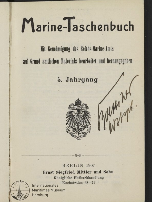 Titelseite eines Buches mit dem Titel „Marine‑Taschenbuch“, darunter gedruckte Angaben „5. Jahrgang“ und Verlagszeile „Berlin 1907, Ernst Siegfried Mittler und Sohn“, ein kaiserlicher Adler als Emblem in der Mitte sowie eine große handschriftliche Signatur rechts; unten links das Logo des Internationalen Maritimen Museums Hamburg.