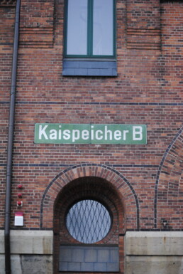 Rote Backsteinfassade mit grünem Schild