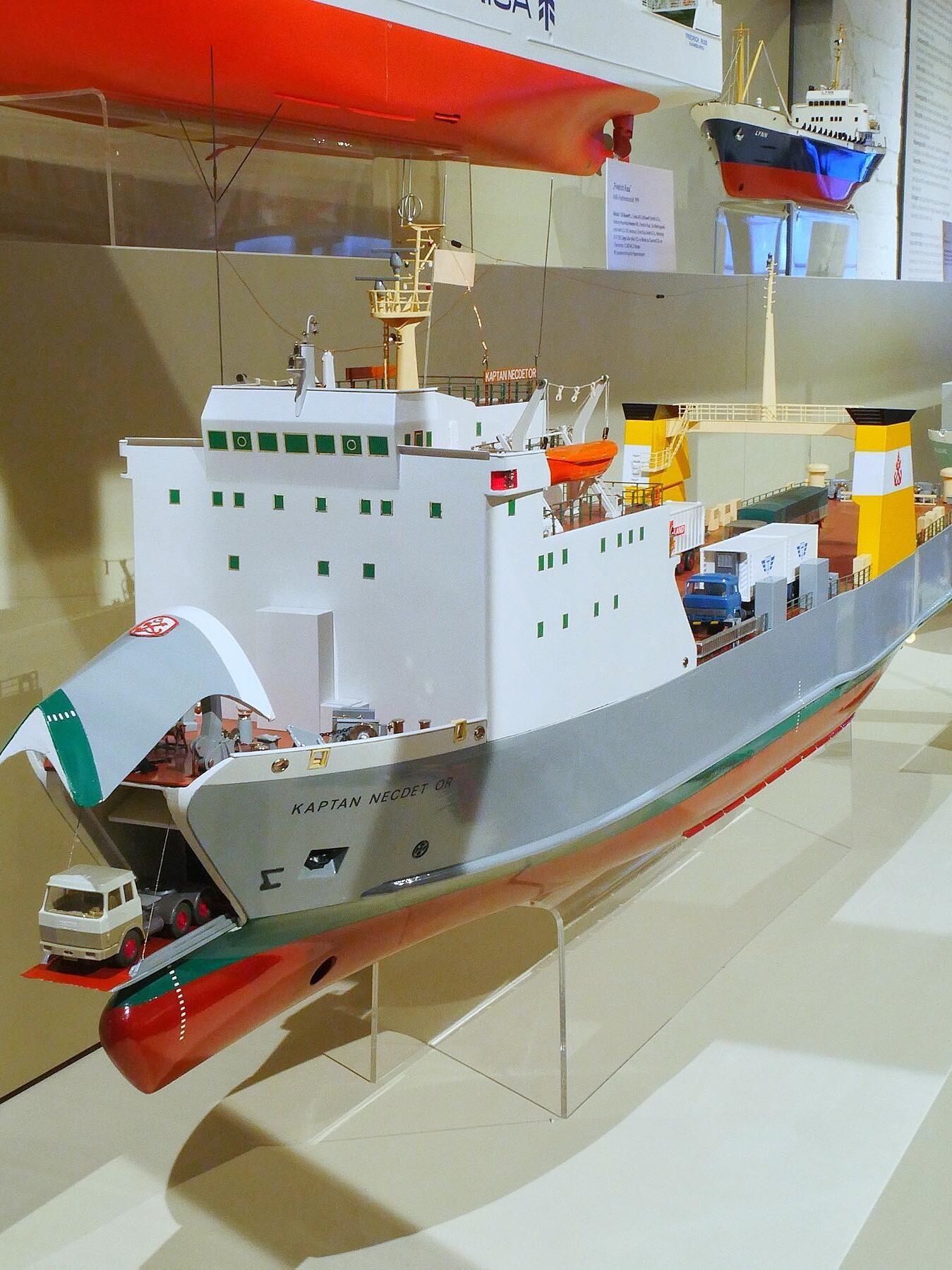 Detailliertes Modell eines RoRo-Frachtschiffs mit geöffneter Rampe, aufgeparktem Lkw und gelben Schornsteinen im Museumsdisplay.