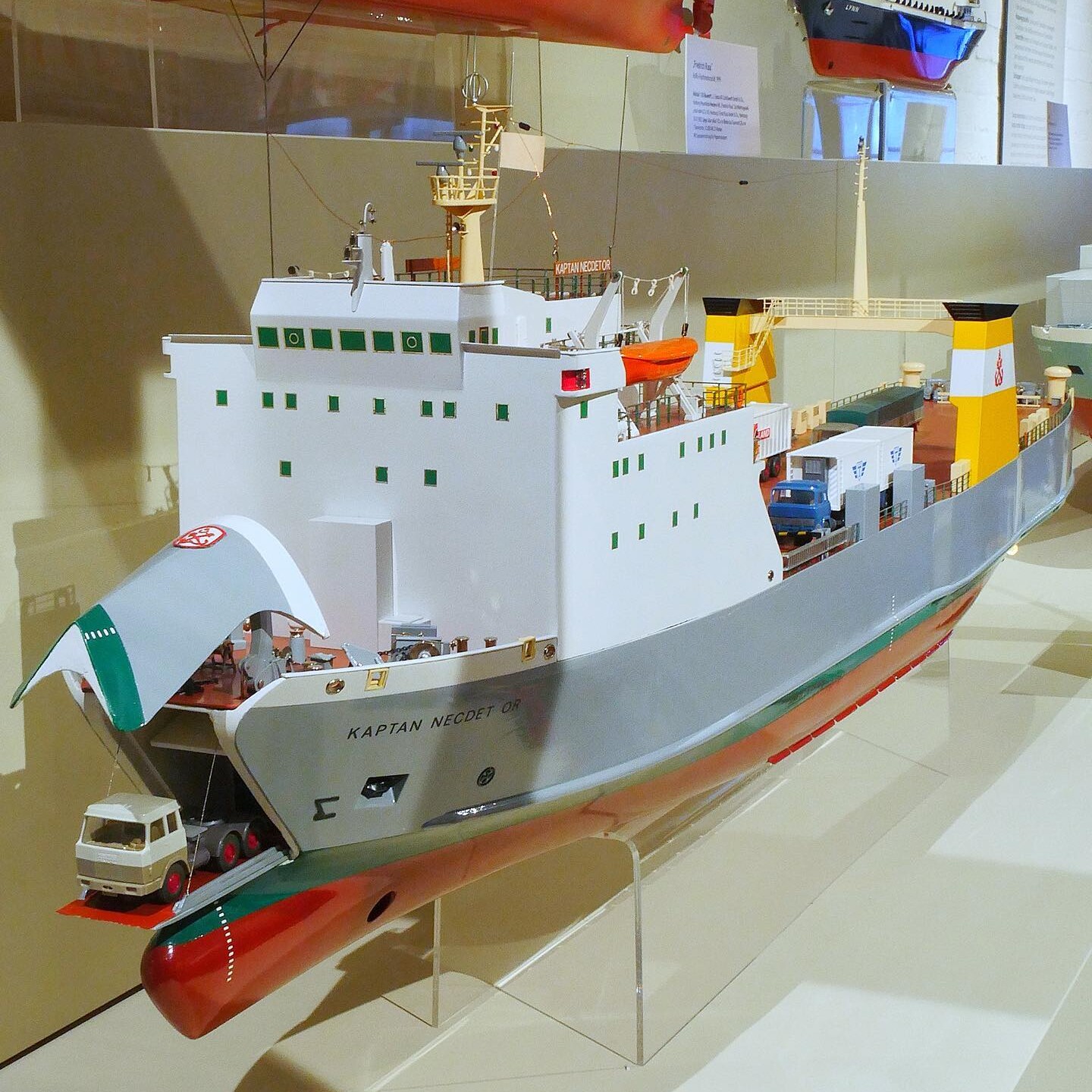 Detailliertes Modell eines RoRo-Frachtschiffs mit geöffneter Rampe, aufgeparktem Lkw und gelben Schornsteinen im Museumsdisplay.