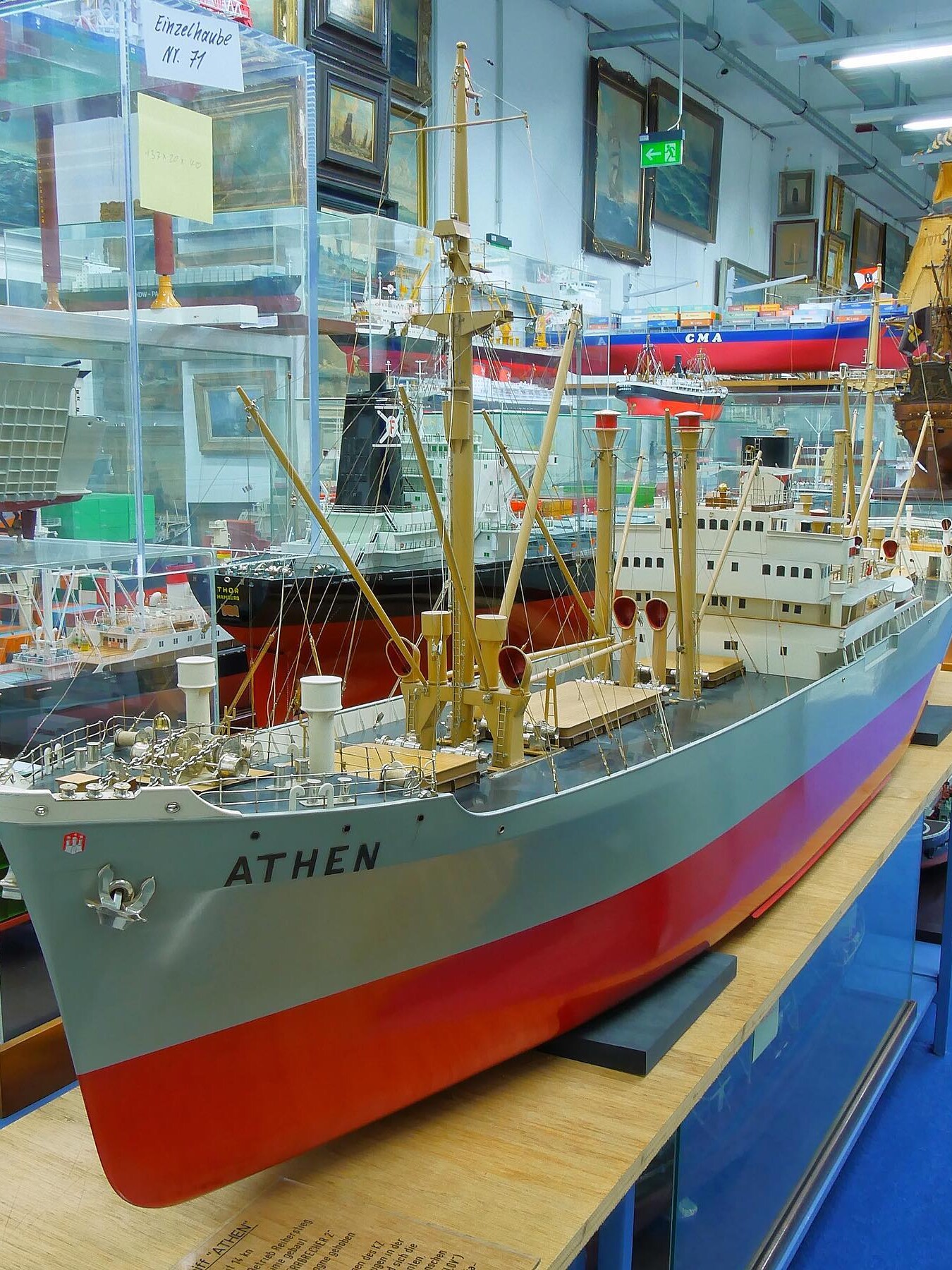 Großes Modellschiff mit Namen ATHEN in Museumsvitrine, sichtbare Masten, Decksaufbauten und rote Wasserlinie.