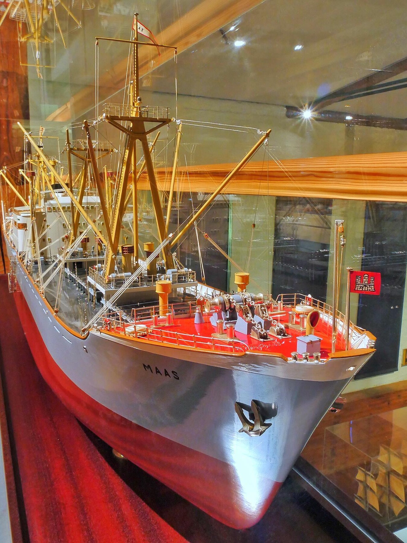 Detailliertes Schiffsmodell mit roten Decks, goldenen Masten, Reling und dem Namen 