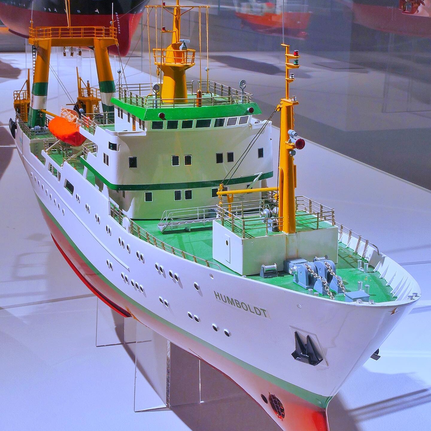 Modell eines weißen Forschungsschiffs mit grünem Deck, gelben Masten und dem Namen HUMBOLDT am Bug, gezeigt in einer Vitrine