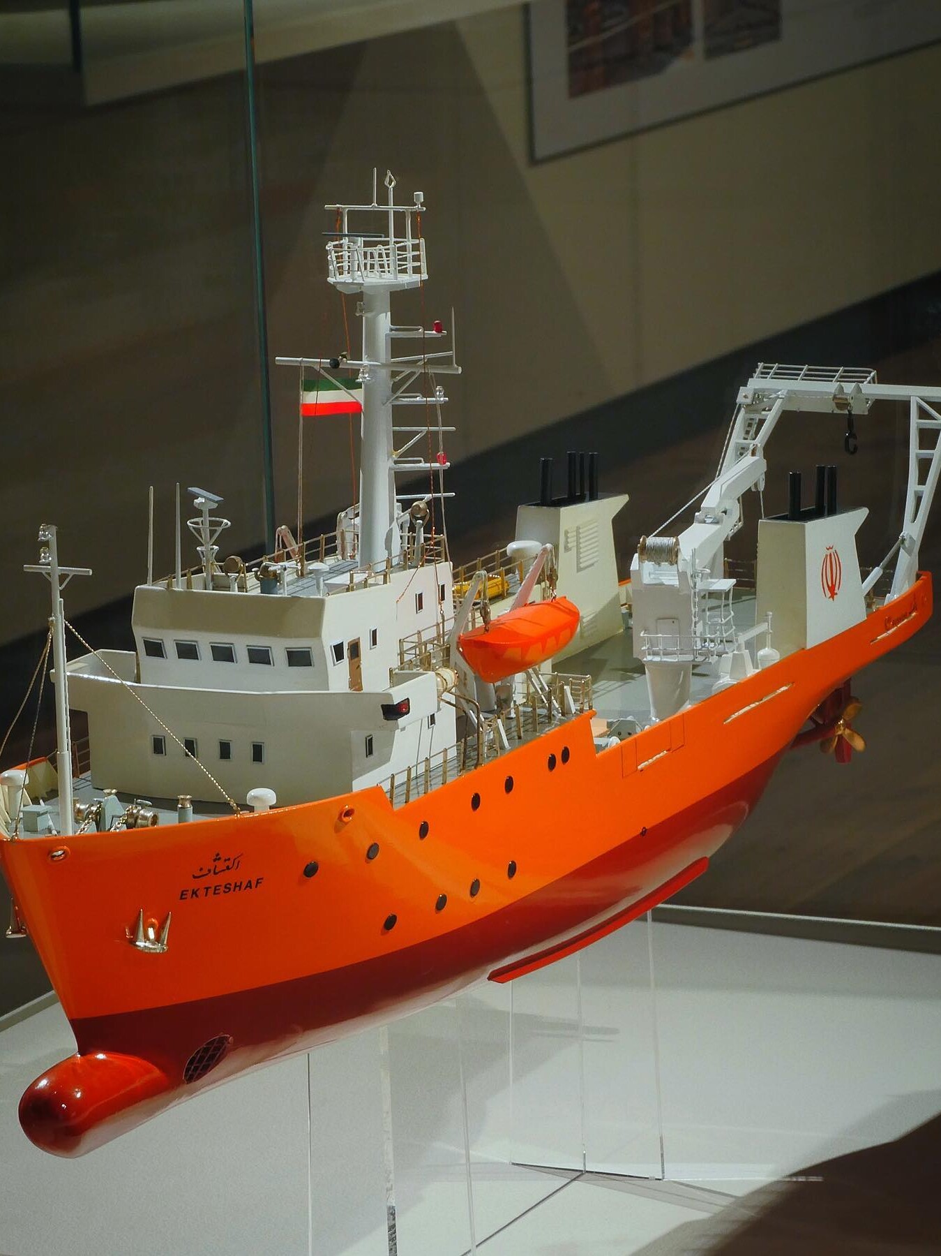 Modell eines orangen Forschungsschiffs mit Brücke, Mast, Rettungsboot und Kranausleger, Beschriftung