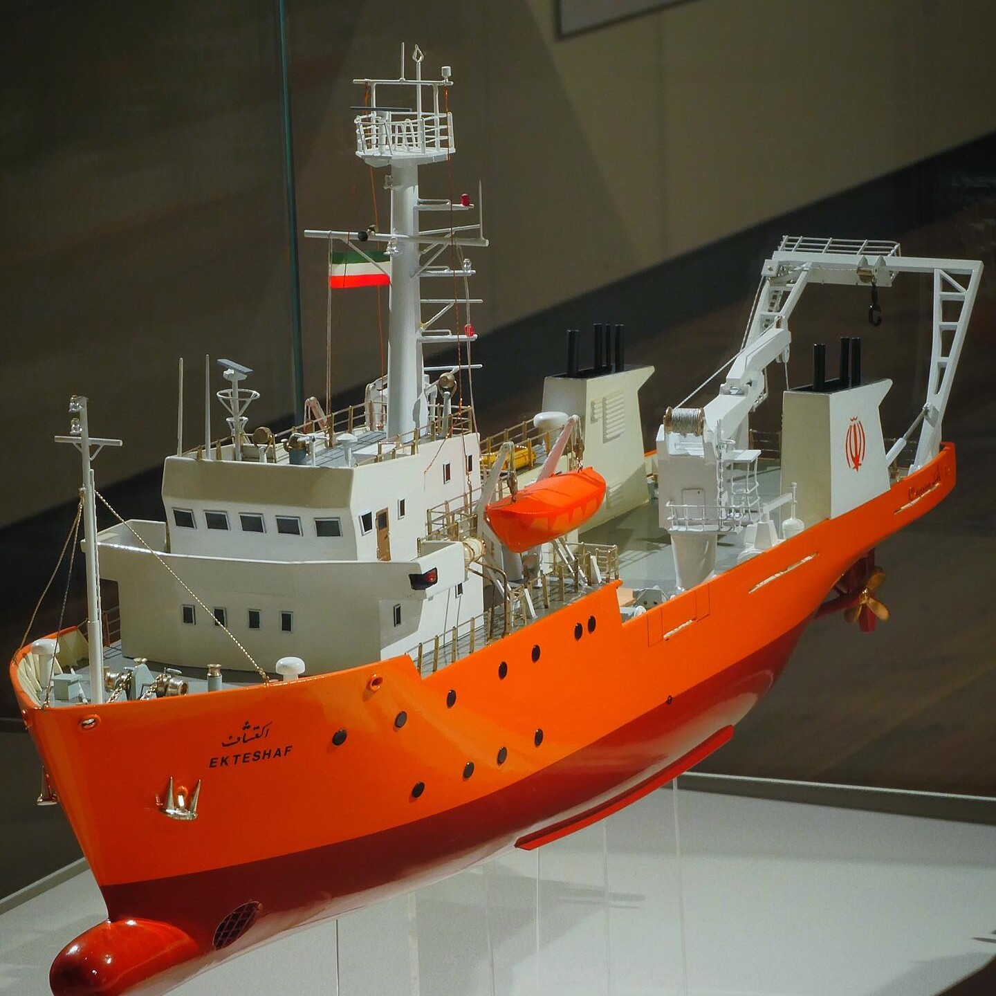 Modell eines orangen Forschungsschiffs mit Brücke, Mast, Rettungsboot und Kranausleger, Beschriftung 