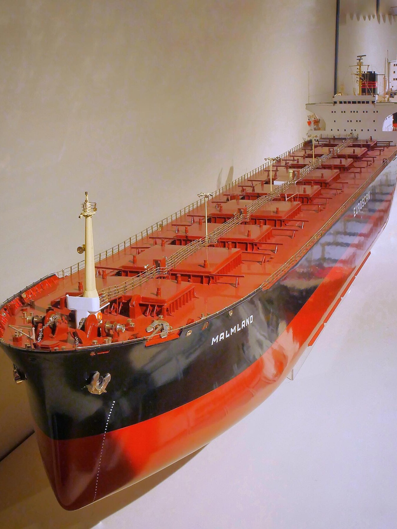 Modell eines großen Frachtschiffs mit rotem Deck und schwarzem Rumpf, Name MALMLAND an der Seite sichtbar, Nahaufnahme von Bug bis Aufbauten.