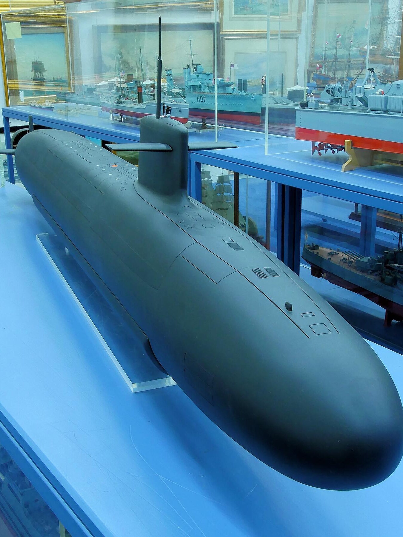 Großes schwarzes U-Bootmodell mit Kommandoturm und Seitenruder in einer Vitrine, im Hintergrund weitere Schiffsmodelle und Gemälde.