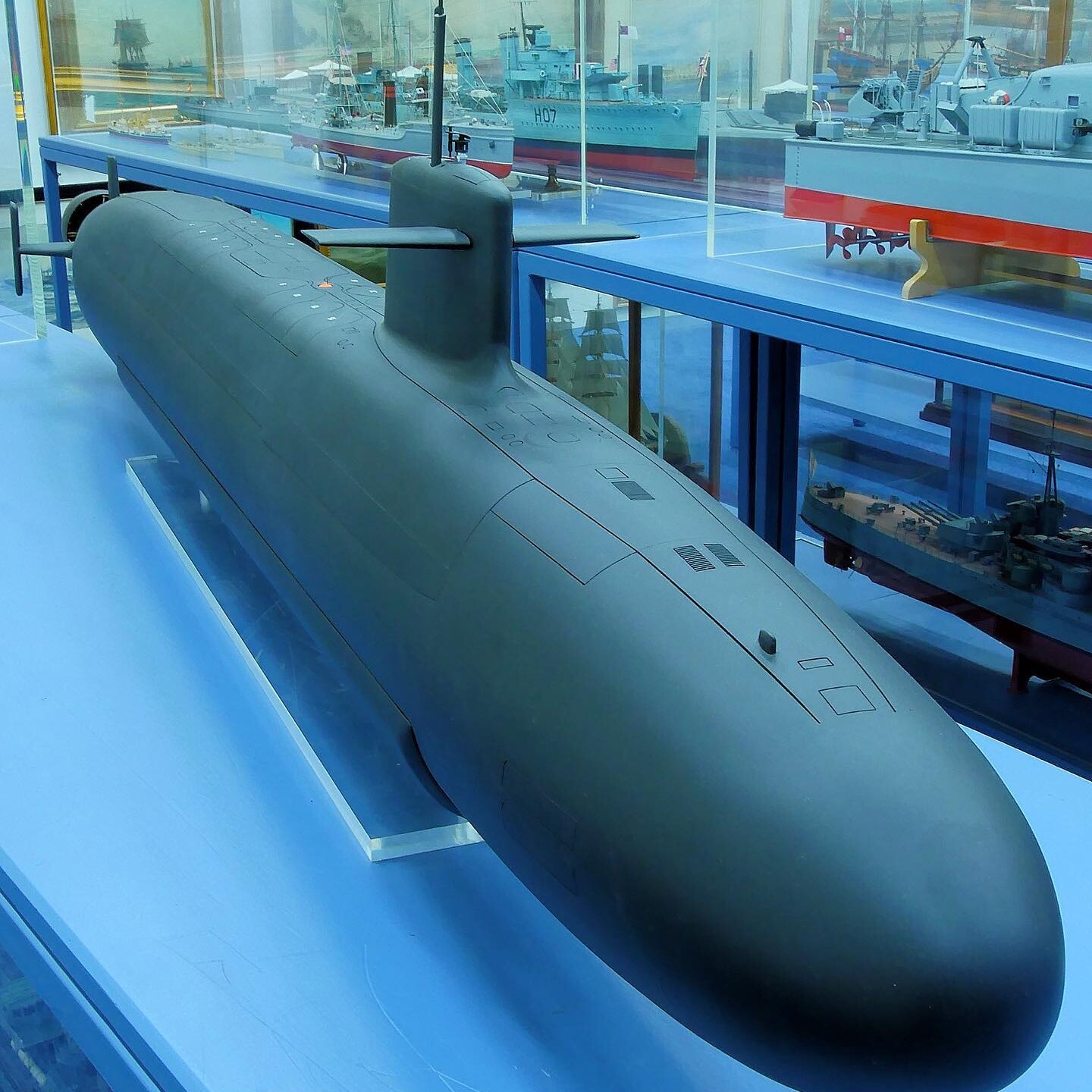 Großes schwarzes U-Bootmodell mit Kommandoturm und Seitenruder in einer Vitrine, im Hintergrund weitere Schiffsmodelle und Gemälde.