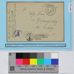 Historische Feldpostkarte mit handschriftlicher Adresse, Poststempel und Museumsetikett auf blauem Hintergrund; Farbkarte unten.