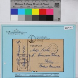 Auf blauem Archivblatt montierte Feldpostkarte mit handschriftlicher Adresse, Stempeln und aufgedrucktem Museumssiegel.