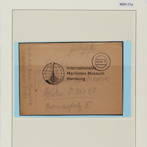 Brauner Briefumschlag mit Globus-Logo, Poststempel und Handschrift, auf hellbeiger Archivkarte montiert; Farbkontrollkarte oben.