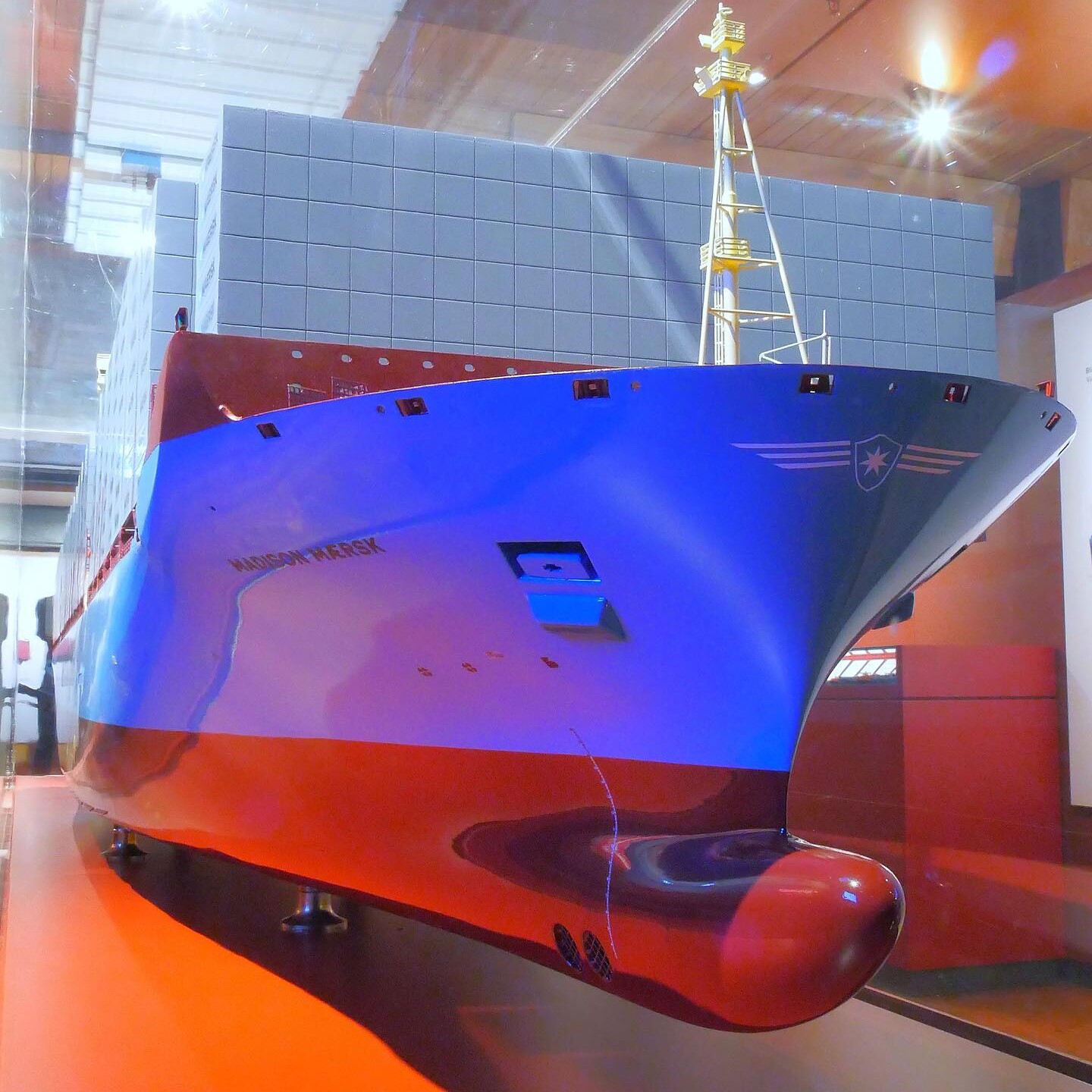 Bugansicht eines großen Containerschiff-Modells mit blau-rotem Rumpf, aufgestapelten Containerkästen und markantem Mast