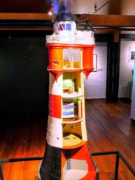 Detailliertes Schnittmodell eines rot-weißen Leuchtturms mit sichtbaren Innendecken, Zimmern, Treppen und Galerie im Museumsraum