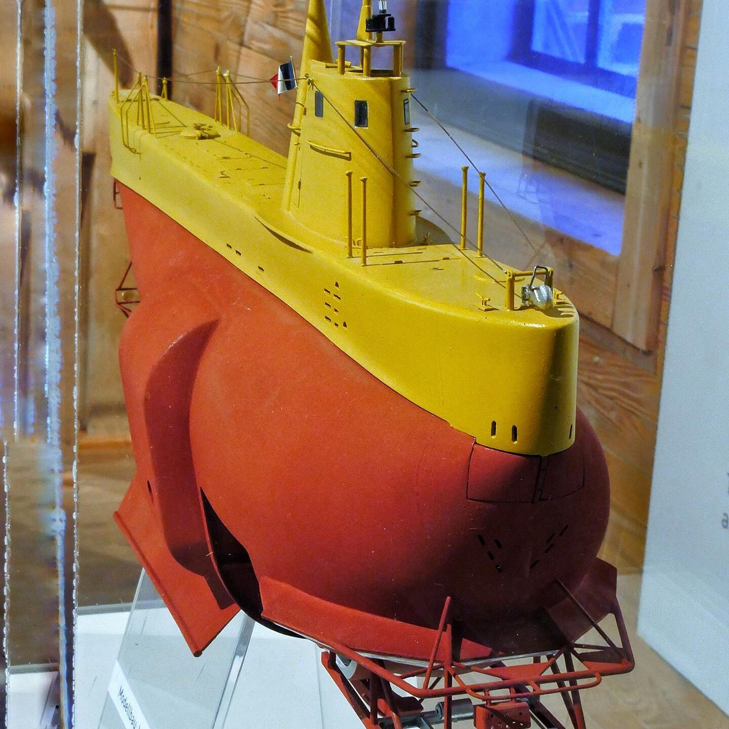 Modell eines roten und gelben Forschungstauchboots mit Turm, Antennen und feinen Relings- und Seil-Details in einer Vitrine