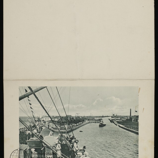 Blick vom Schiffsdeck auf Hafenkanal in Bremerhaven mit Passagieren an Bord, Menschen an der Kaimauer und einem Boot.
