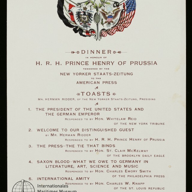 Abendessenmenü mit gekreuzten deutschen und US‑Flaggen über einem Wappen, darunter eine Liste von Toasts und Gastrednern.